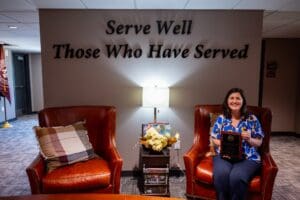 A person sits in a chair holding an award plaque.
